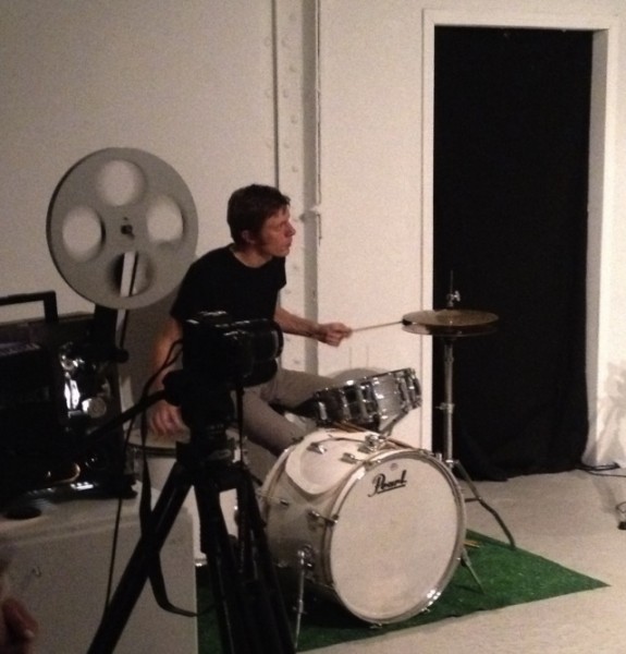 Tim Nickodemus playing drums on astro-turf in STUDIO AUDIENCE (WEATHER PATTERNS) by Andrew Mausert-Mooney at Johalla Projects 